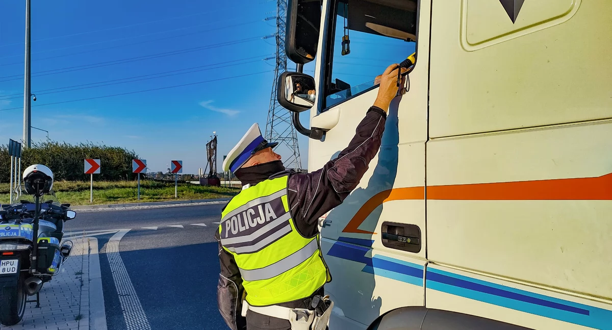Zdjęcie przedstawia policjanta kontrolującego trzeźwość kierowcy