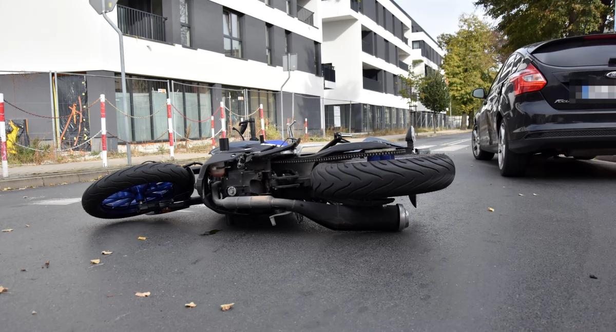 Zdjęcie przedstawia samochód osobowy i motocykl po zderzeniu