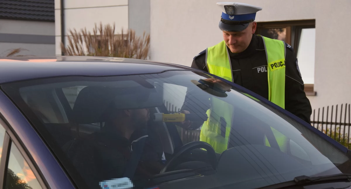 Zdjęcie przedstawia policjanta kontrolującego trzeźwość kierowcy
