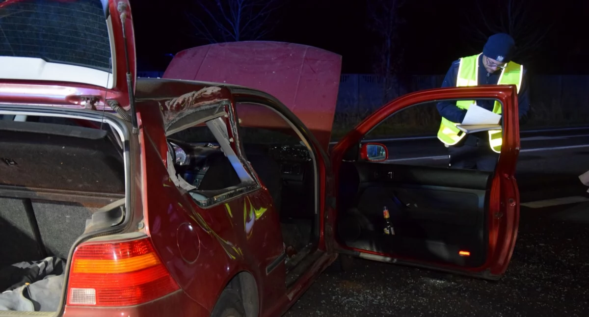 Zdjęcie przedstawia samochód marki volkswagen po kolizji na obwodnicy Kościana przy którym stoi policjant