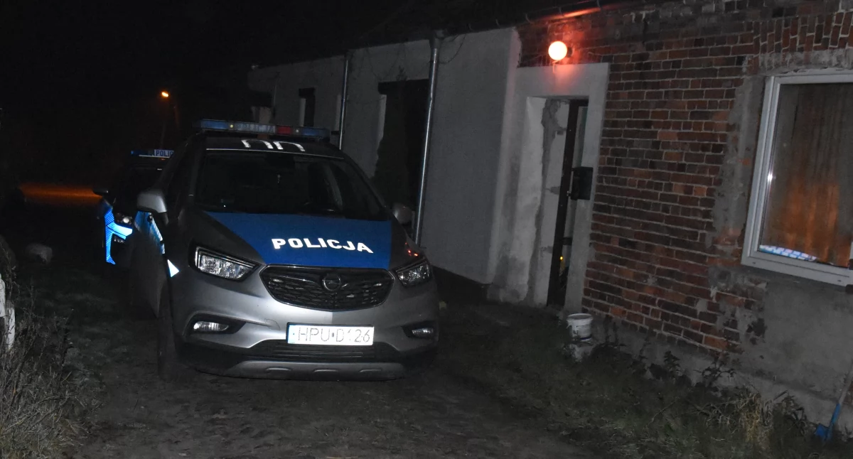 Zdjęcie przedstawia radiowóz stojący przed domem w któym doszło do pobicia ze skutkiem śmiertelnym