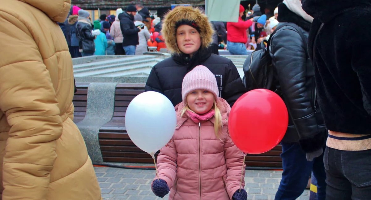 Zdjęcie przedstawia dzieci z biało-czerwonymi balonami podczas obchodów Święta Niepodległości w Kościanie