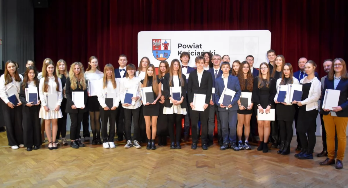 Zdjęcie przedstawia uczniów i studentów, którzy otrzymali stypendia i nagrody powiatu kościańskiego