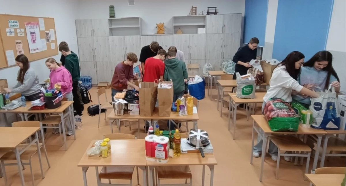 Zdjęcie przedstawia uczniów Szkoły Podstawowej nr 4 w Kościanie przygotowujących świąteczne paczki dla potrzebujących