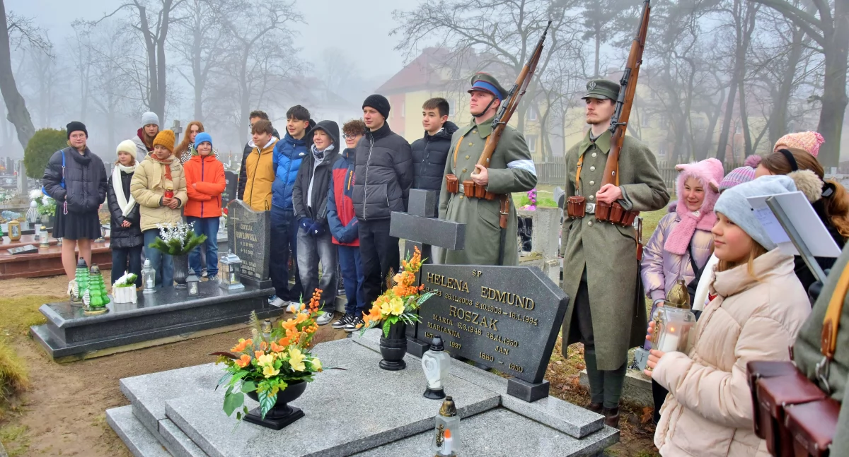 Zdjęcie przedstawia uroczystość ustawienia pamiatkowej tabliczki przy grobie powstańca na cmentarzu w Kościanie z udziałem uczniów