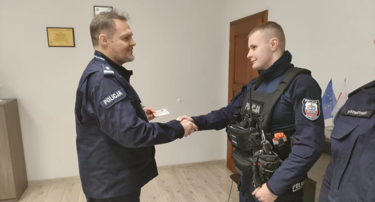 Zdjęcie przedstawia komendanta Roberta Przyjemskiego gratulującego Albertowi Giemzie.